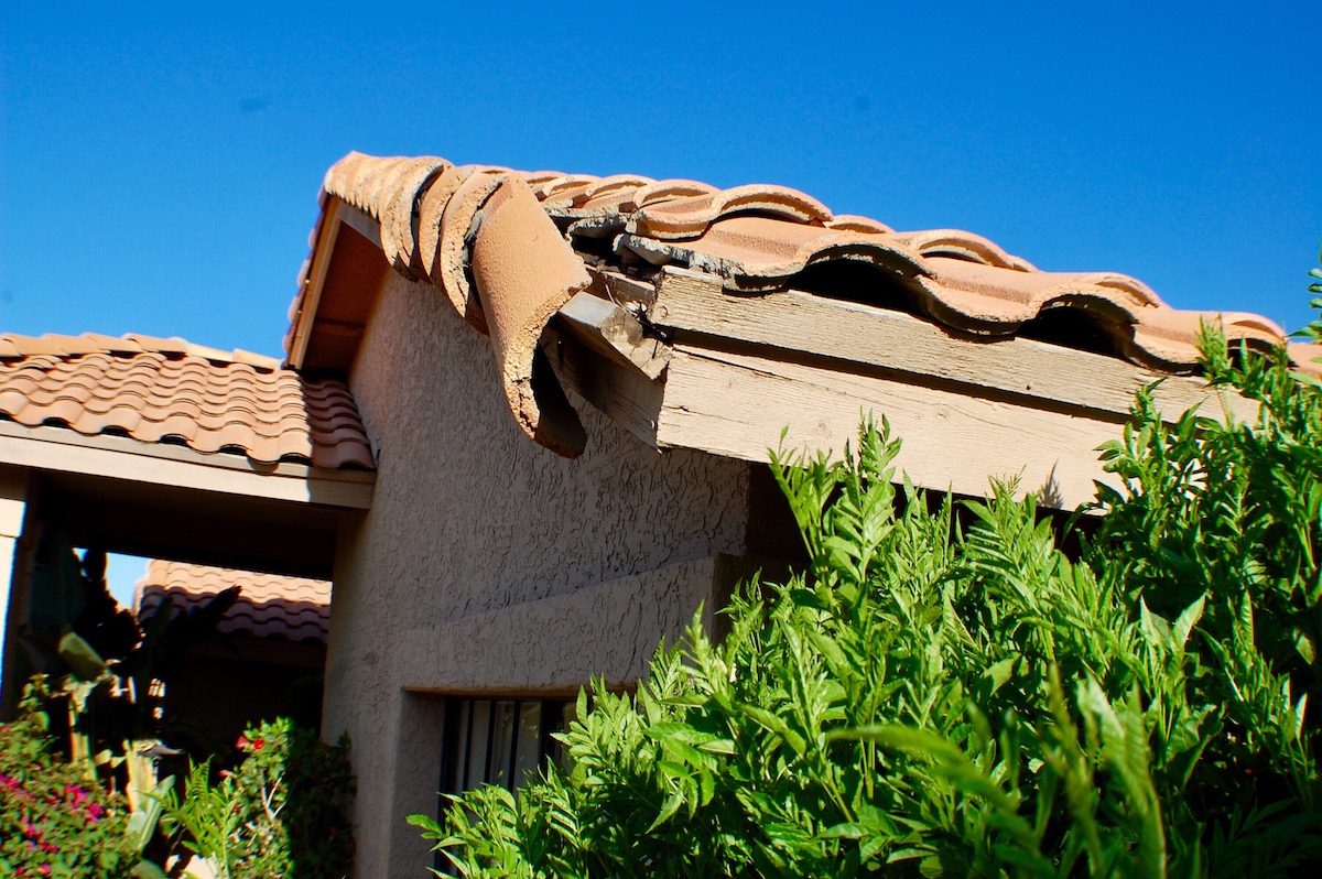 A close up of a tile roof with damage from a storm.