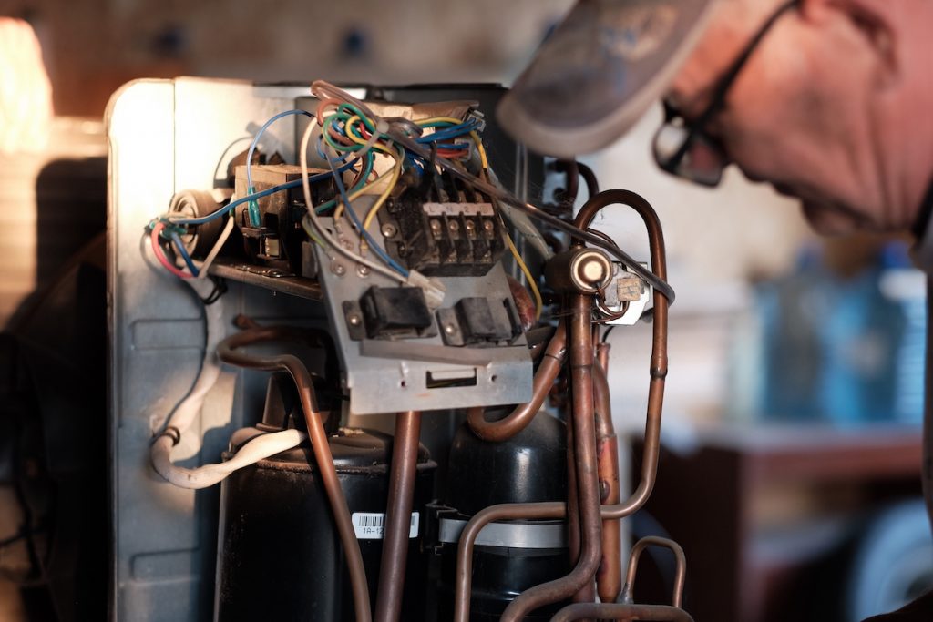 A person leaning over an air conditioning interior system. 