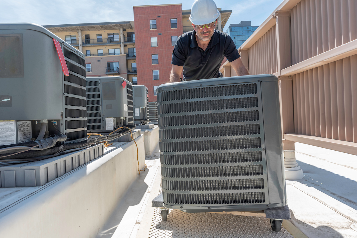  A contractor moving an AC unit on wheels.