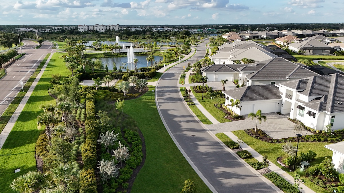 Aerial view of a planned community with homes, landscaped streets, and a shared pond.